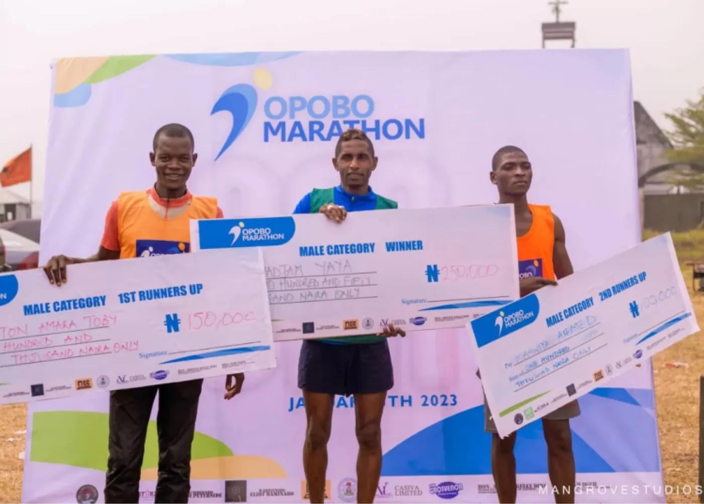 The top three men holding prize cheques at Opobo Marathon 2023